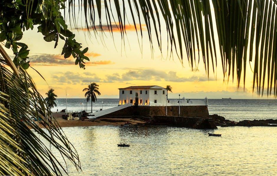 White Illuminated House on the Sea and Palm Leaves in Foreground